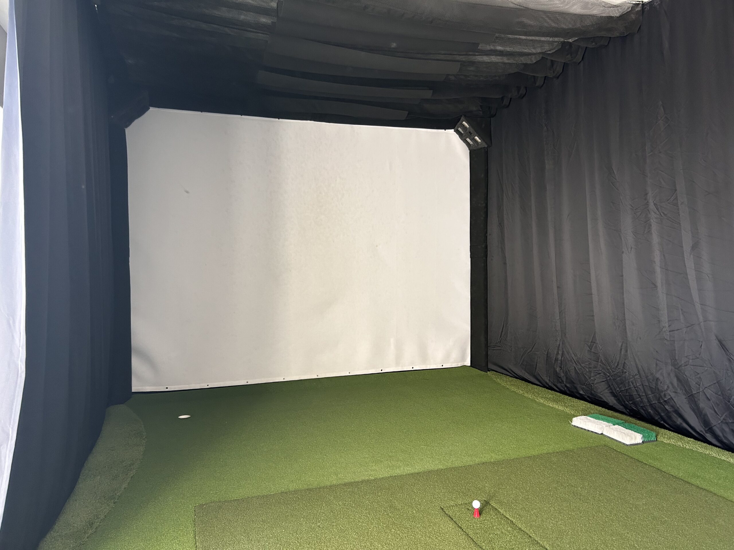 In-home golf simulator hitting bay with impact screen